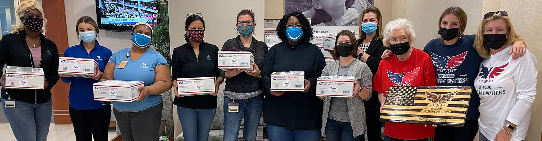 A group of Sagicor volunteers displays boxes packed for the Operation: Military Matters organization.